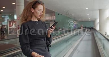 年轻女孩在机场使用智能手机。 带行李的快乐欧洲女人在<strong>终点</strong>站使用移动电话。
